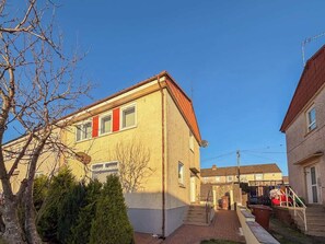 A two-story residential building with a brick facade, a visible satellite dish, and a small front yard with a tree and shrubbery. - The Bridge- 3 Bedrooms in Coatbridge with Driveway (Coatbridge)