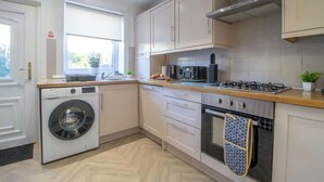 A modern kitchen with a washing machine, oven, and gas stove.