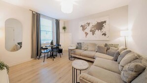 Una sala de estar moderna con un sofá, una mesa redonda de centro, un área de comedor con sillas, un mapa mundial en la pared y un ventanal grande.