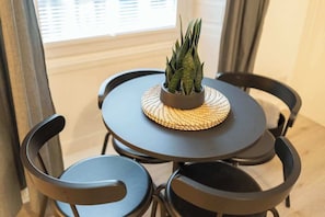 A round table with a woven placemat, surrounded by four black chairs. - The Green- 2 Bed Flat near Aberdeen Ferry Terminal (Aberdeen)