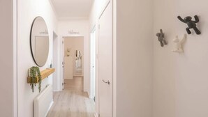 Un pasillo con un espejo, un letrero de bienvenida, una planta y una puerta.