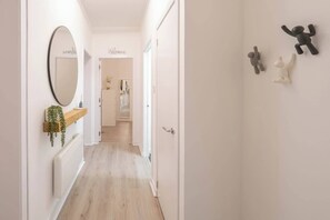 A hallway with a mirror, a welcome sign, a plant, and a door. - The Green- 2 Bed Flat near Aberdeen Ferry Terminal (Aberdeen)