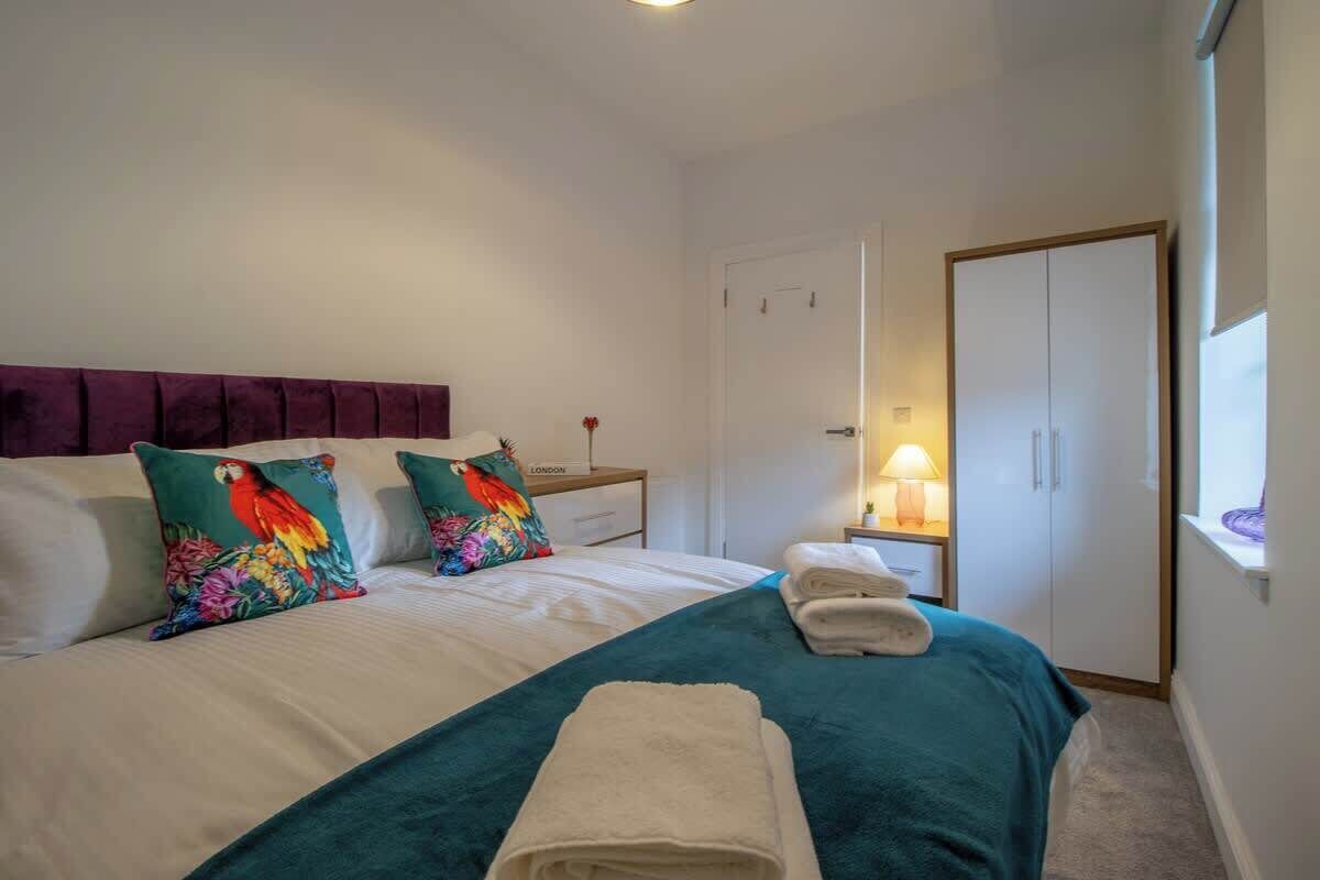 Een netjes opgemaakt bed met kussens, een bedlampje en een kledingkast in een hotelkamer.