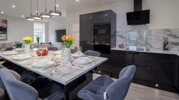 A modern kitchen with a built-in oven, a black range hood, and a marble countertop. - William Wallace View - 5 Bedroom House Near Castle (Stirling)