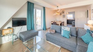 A modern living room with a sofa, glass coffee table, and a flat-screen TV. - 3-bedroom Sunny Apartment in Knokke (Knokke-Heist)