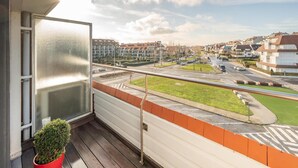 A balcony with a view of a residential area, a road, and a clear sky. - 3-bedroom Sunny Apartment in Knokke (Knokke-Heist)