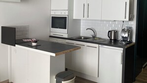 Une cuisine moderne avec des meubles blancs, un four encastré, un évier et une machine à café.