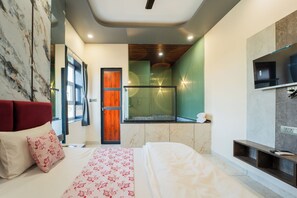 A modern hotel room with a bed, a wooden door, a glass shower enclosure, and a marble wall. - Hotel Galaxy 700 (Danta Ramgarh)