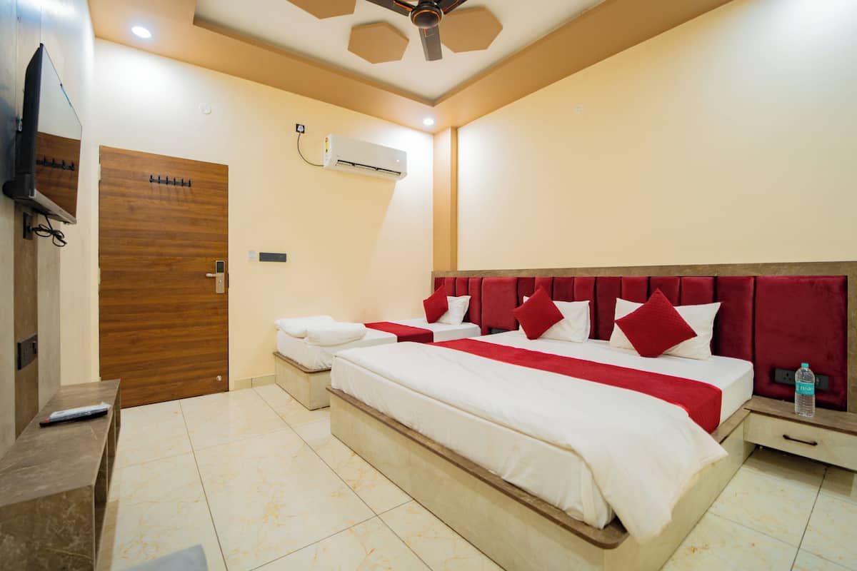 A hotel room with a large bed, a TV, an air conditioning unit, and a wooden door.