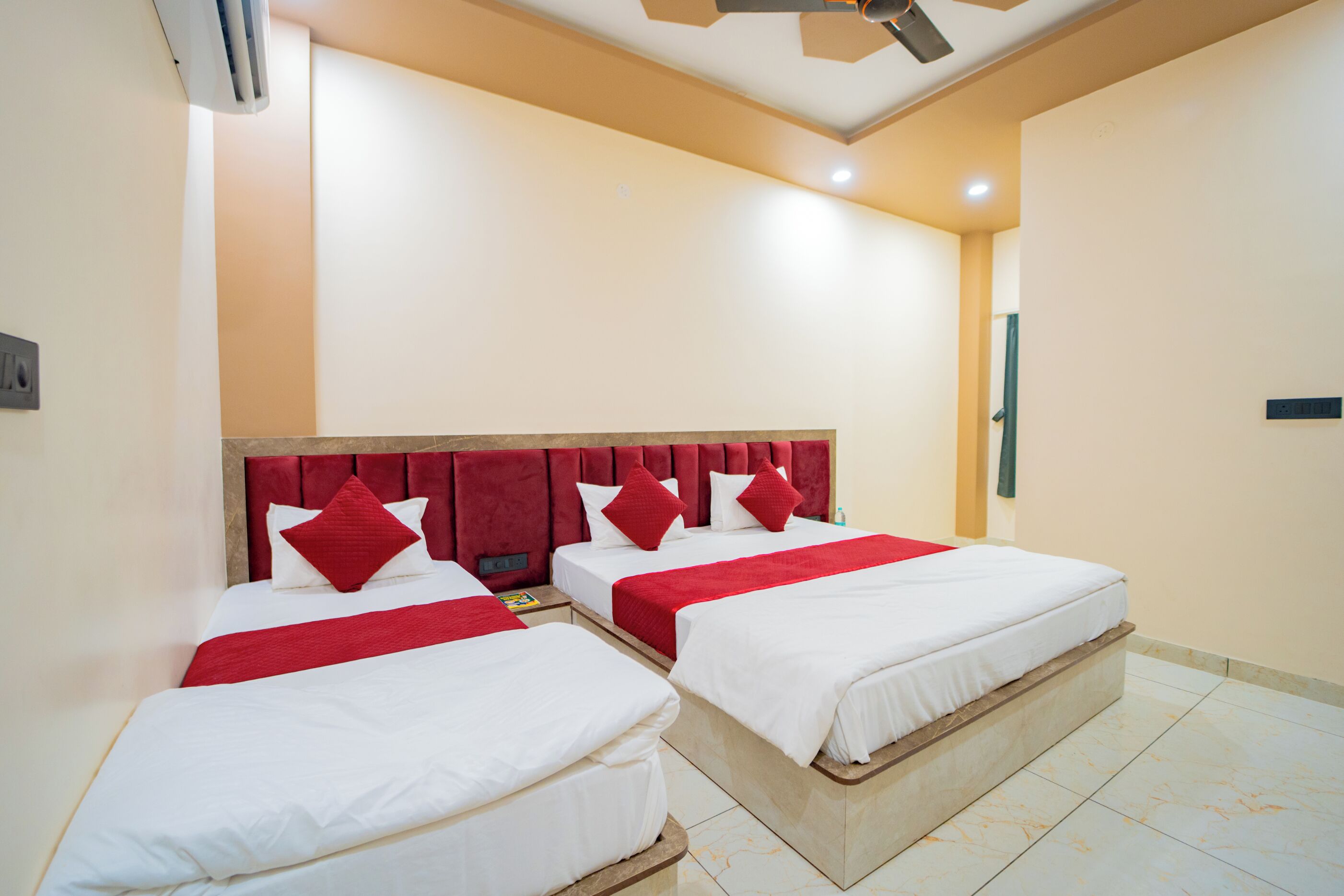 A hotel room with two beds, each with a red headboard and white bedding.