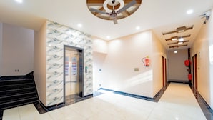 A hotel corridor with a marble floor, a ceiling fan, and a wall-mounted elevator.