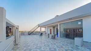 A rooftop terrace with patterned flooring, a staircase, and seating areas.