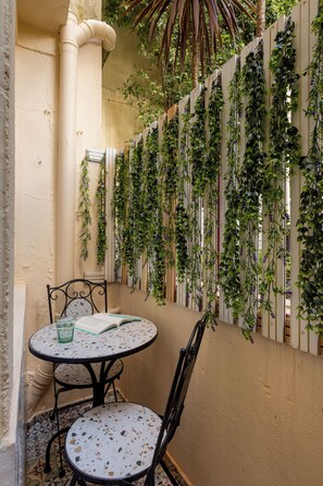 Un petit espace extérieur aménagé avec une table ronde et des chaises, le tout entouré d’un mur orné de plantes grimpantes.