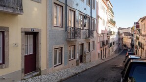 Una calle estrecha flanqueada por edificios de varios pisos, cada uno con balcones y una variedad de estilos de ventanas.