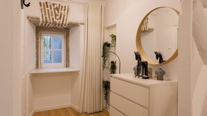 Un baño con ventana, espejo y tocador blanco con cajones.