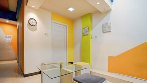 A modern reception area with a glass table, a clock, and a bench. - Hotel O near Terminal Batoh formerly (Banda Aceh)