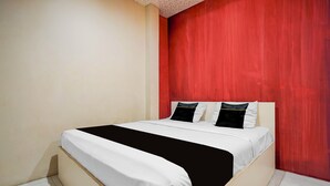 A bed with white bedding and black accents, a red accent wall, and a white ceiling. - Hotel O near Terminal Batoh formerly (Banda Aceh)