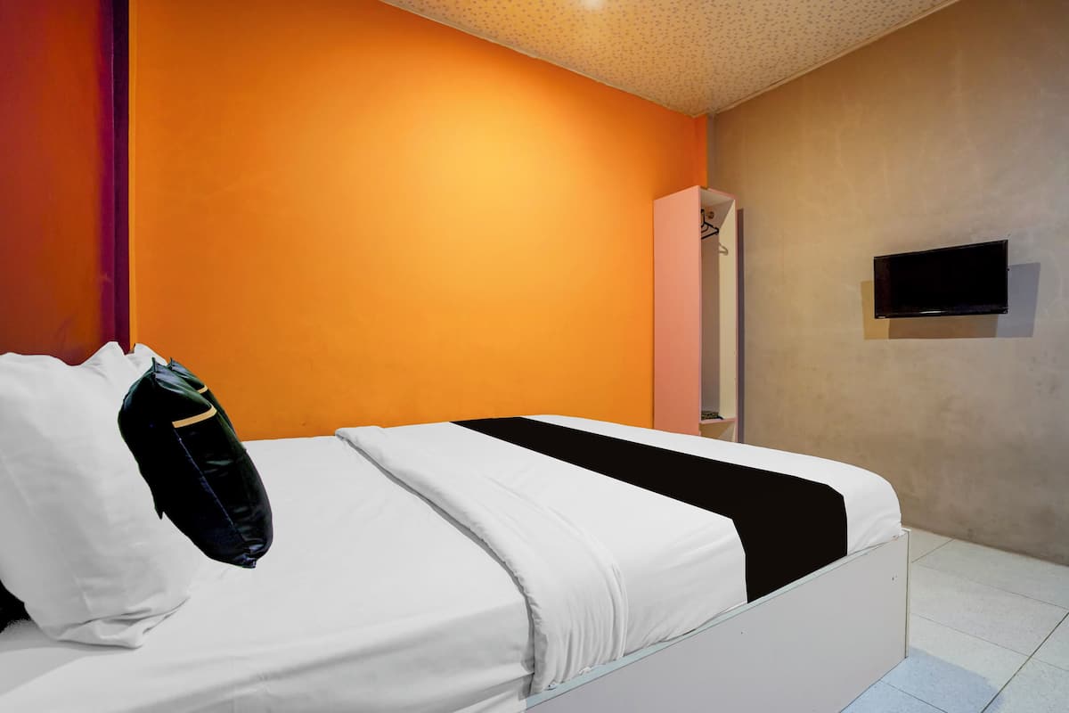 Una habitación de hotel con una cama, un armario y un televisor montado en la pared.