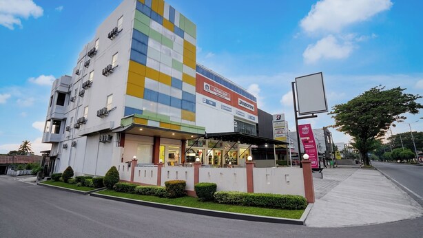 A multi-story hotel with a modern facade, air conditioning units, and a covered entrance. - Hotel O near Terminal Batoh formerly (Banda Aceh)