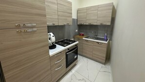 Une cuisine de taille réduite, dotée de meubles en bois, d’une cuisinière à gaz, d’un évier et d’une machine à café.