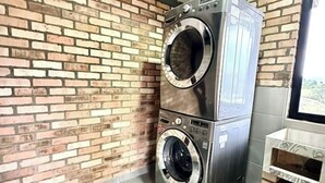 Una lavadora y secadora apiladas frente a una pared de ladrillo.