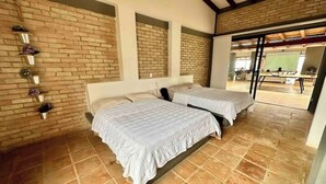 Una habitación con dos camas, una pared de ladrillo y piso de baldosas.