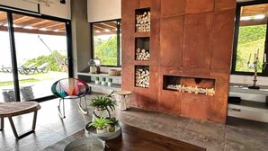 Una sala de estar moderna con chimenea, ventanas amplias y vistas al exterior.