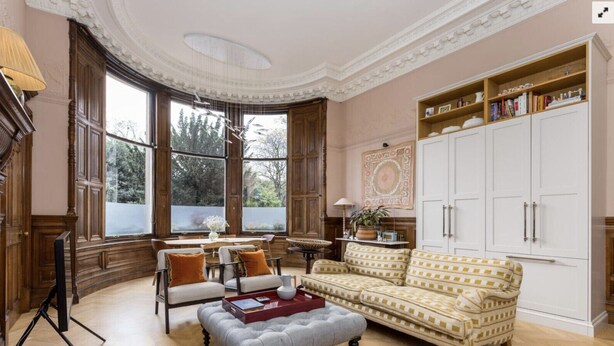 A spacious living room with a large window, a sofa, a dining table, and a bookshelf. - Luxury Flat Overlooking Eglinton Gardens (Edinburgh)
