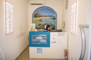 A reception desk with a scenic backdrop, a blue sign, and a framed certificate. - Miramare Castellabate Resort (Castellabate)