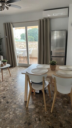 Een moderne keuken met een inbouwkoelkast, een plafondventilator en een eethoek met een tafel gedekt voor twee personen.