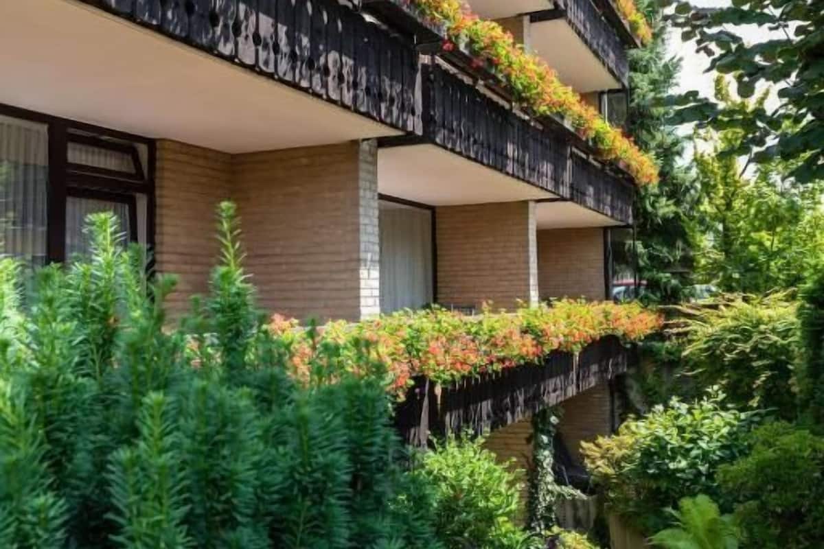 A multi-story building with balconies adorned with plants and flowers.