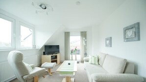 A modern living room with a sofa, armchair, and a coffee table. - Appartementhaus Bahlo (Bad Bevensen)