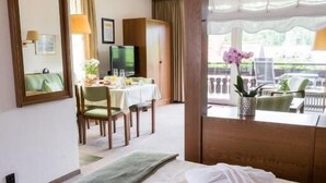 A hotel room with a bed, a dining area, a TV, and a window with a view. - Appartementhaus Bahlo (Bad Bevensen)