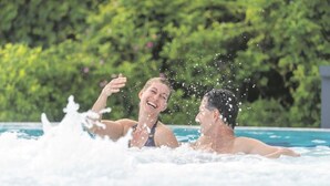 A couple in a swimming pool with water splashing around them. - Appartementhaus Bahlo (Bad Bevensen)