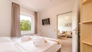Une chambre d’hôtel avec un lit, une télévision, une fenêtre avec des rideaux et une vue sur l’extérieur.