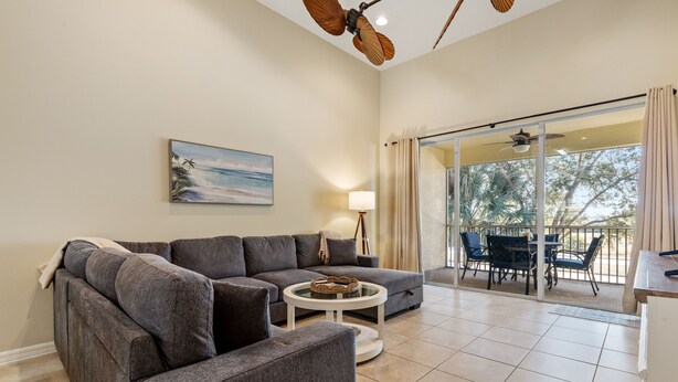 Ein Wohnzimmer mit einem grauen Ecksofa, einem runden Couchtisch und einem Gemälde mit einer Strandansicht.