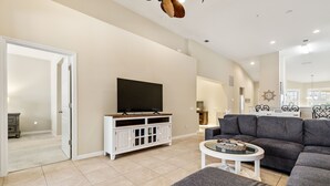 Ein geräumiges Wohnzimmer mit grauem Sofa, einer weißen Unterhaltungseinheit und einem Flachbildfernseher.