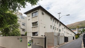 A multi-story building with a gated entrance, a brick pathway, and a street lamp. - Serene Green Point Stay |Quiet, Walkable and Central (Cape Town)
