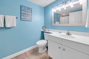 Un bagno con una parete blu, sanitari bianchi, uno specchio grande e un porta asciugamani.