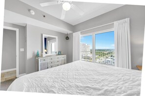 Camera da letto con un letto grande, una cassettiera, una ventola a soffitto e una finestra con vista sulla città.
