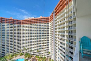 Un hotel di grandi dimensioni con numerosi balconi, una piscina e un cielo azzurro limpido.