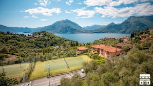 A residential area with a tennis court, houses, and mountains in the background. - General Terms and Conditions - Vacation Rental:Welcome to our vacation rental. To ensure a pleasant and hassle-free stay, please review the following general terms and conditions.Assistance ServicesIn-person assistance: Available from 9:00 AM to 6:00 PMT (Perledo)