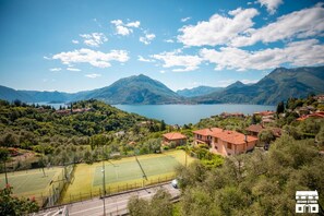 A residential area with a tennis court, houses, and mountains in the background. - General Terms and Conditions - Vacation Rental:Welcome to our vacation rental. To ensure a pleasant and hassle-free stay, please review the following general terms and conditions.Assistance ServicesIn-person assistance: Available from 9:00 AM to 6:00 PMT (Perledo)