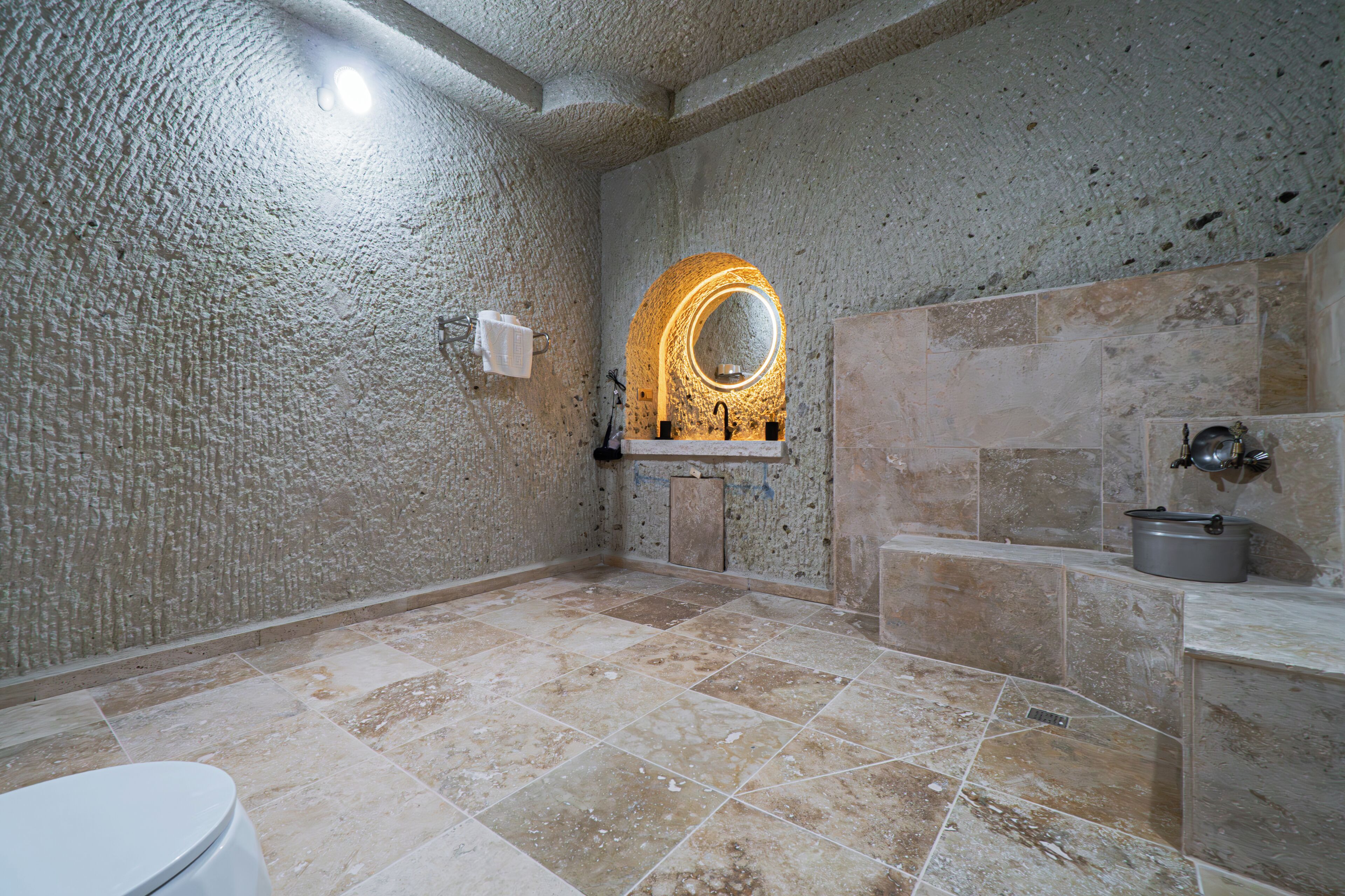 A bathroom with a textured wall, a sink with a mirror, and a toilet.