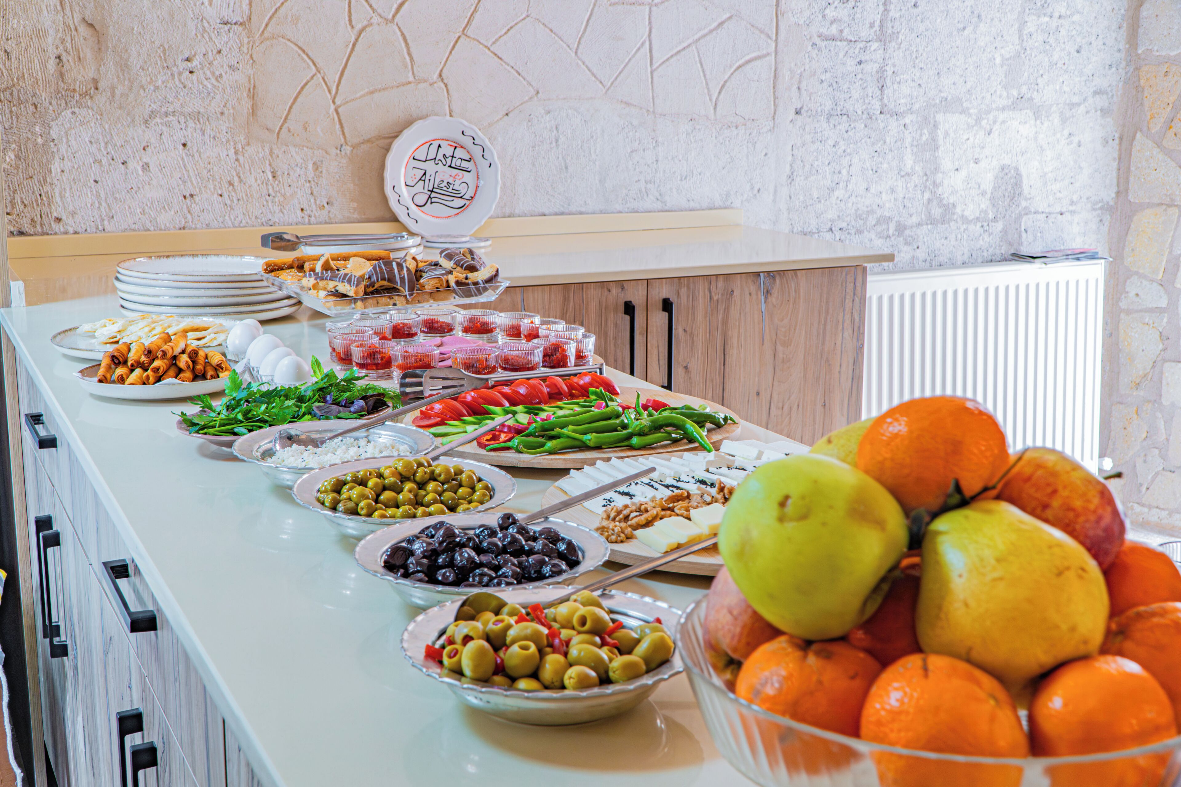 A buffet table with various food items and a fruit bowl.
