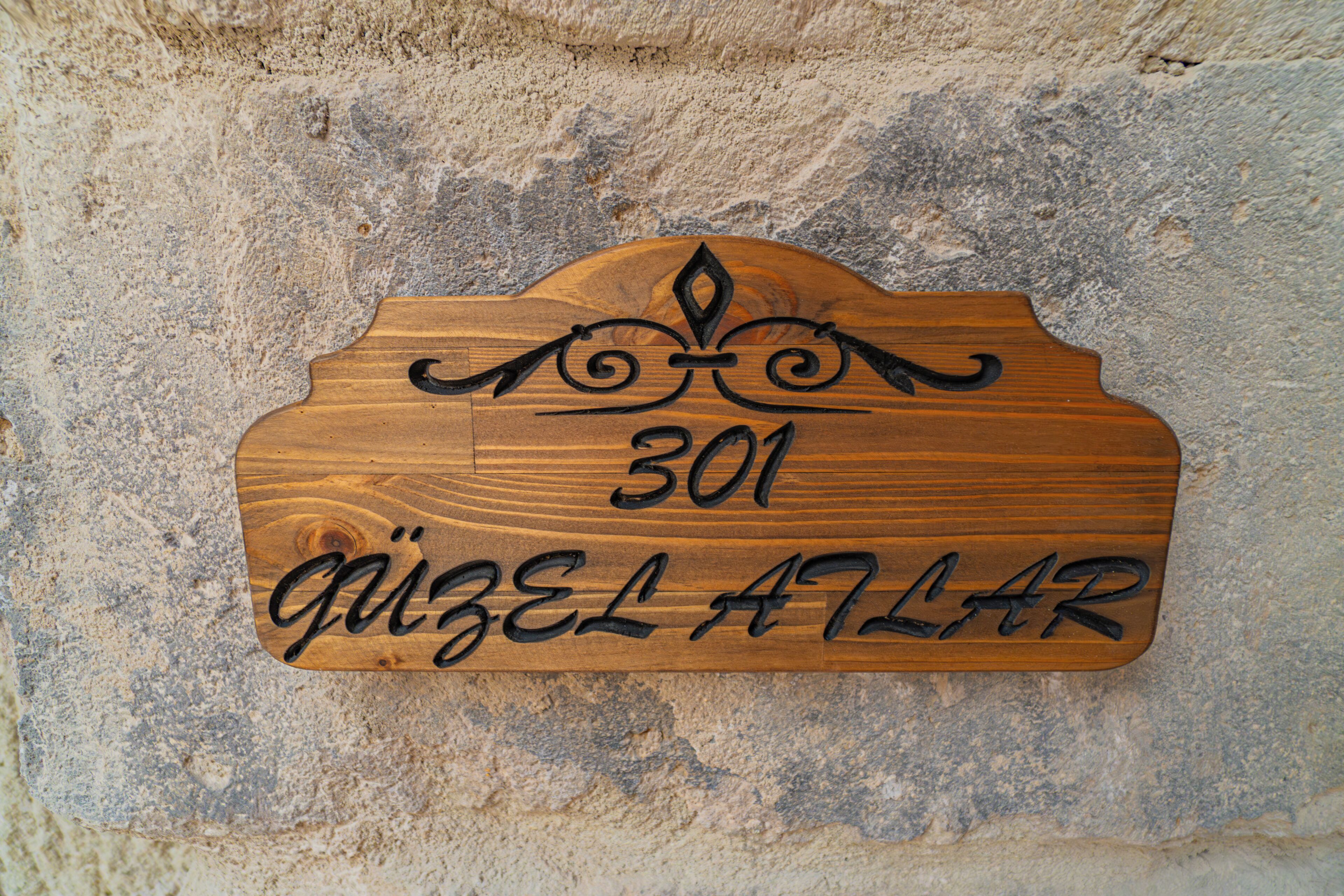 A wooden sign with the number 301 and the name 'Quizel Atlar' on a textured wall.