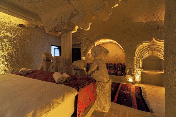 A room with a bed, a stone statue, and a patterned rug.