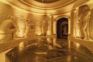 A marble-floored atrium with classical statues and intricate wall carvings.