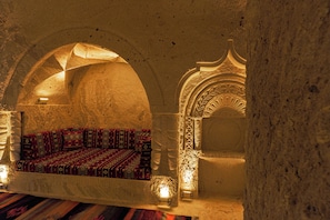 A room with a stone wall, an arched alcove, and a bed with patterned bedding. - Tyana Cave House (Nevsehir)