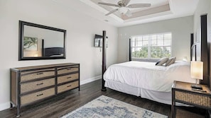 A bedroom with a bed, dresser, mirror, ceiling fan, window, and nightstand. - Pirate's Cove (Punta Gorda)